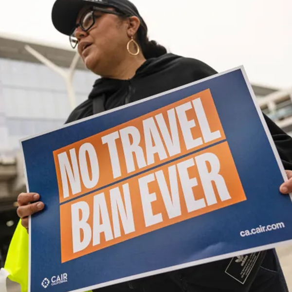 person holding sign that says: no travel ban ever